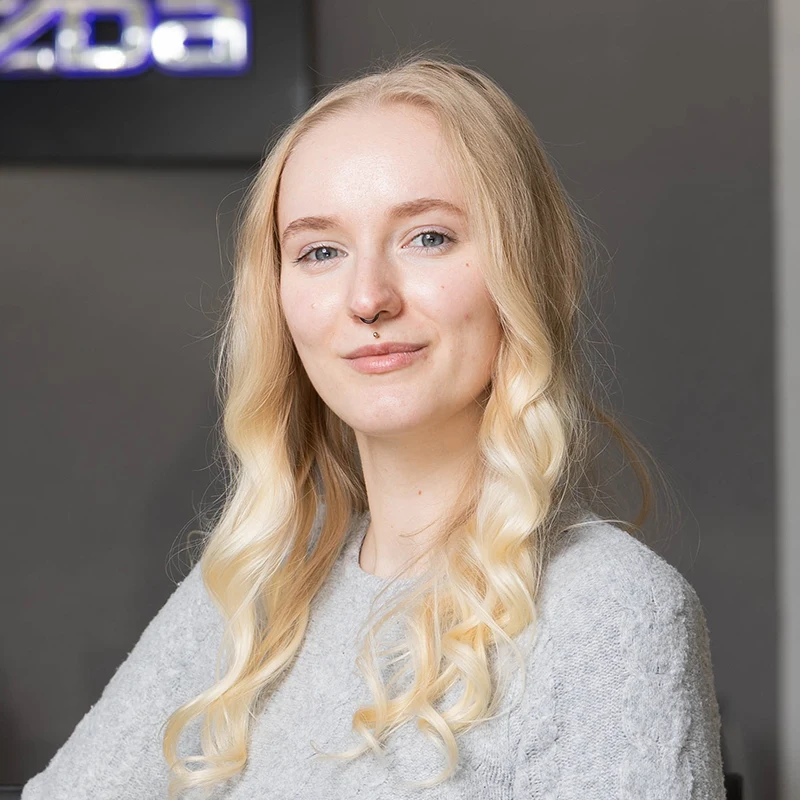 Junge Frau mit hellblonden Haaren lächelt freundlich.